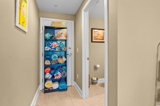 hall featuring light tile patterned floors and baseboards