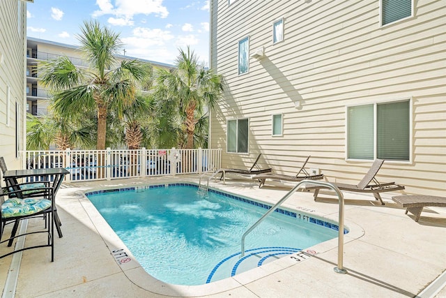 view of swimming pool with a pool, fence, and a patio