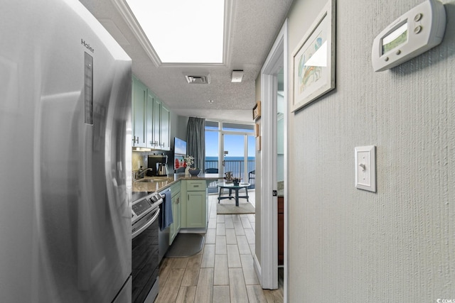 kitchen with visible vents, green cabinets, wood finish floors, stainless steel appliances, and a textured ceiling