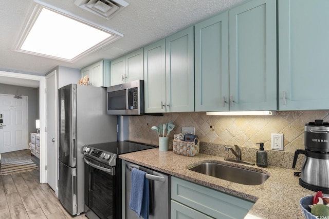 kitchen featuring light stone counters, backsplash, appliances with stainless steel finishes, and a sink