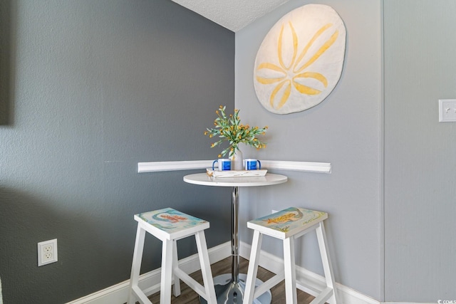 dining space with wood finished floors, baseboards, and a textured ceiling