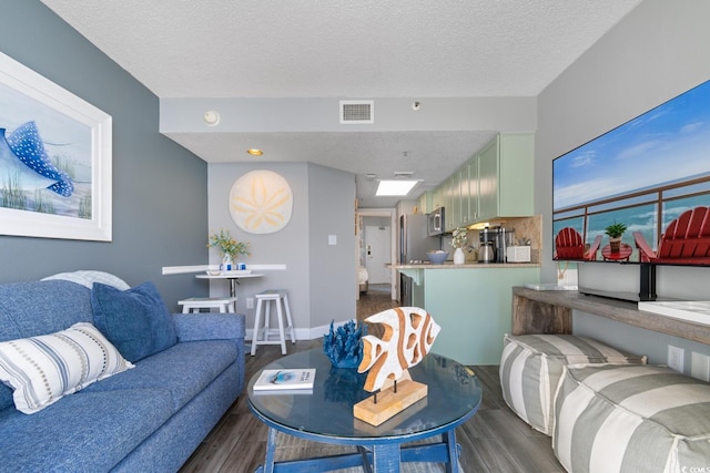 living area with wood finish floors, visible vents, and a textured ceiling