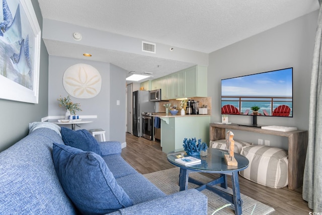 living room featuring visible vents, a textured ceiling, and wood finished floors