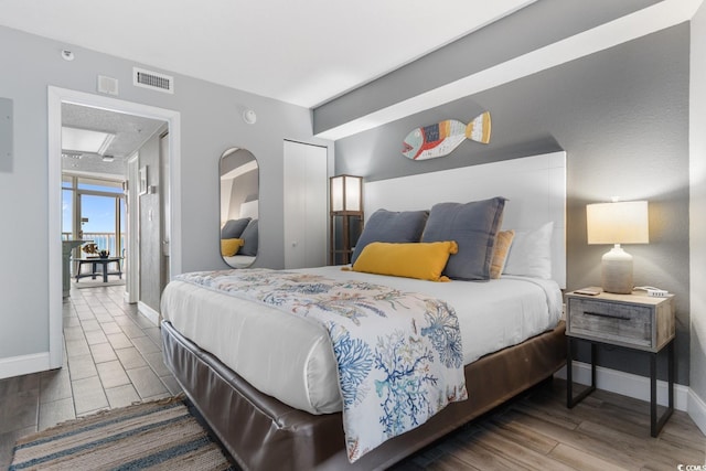 bedroom with a closet, visible vents, baseboards, and wood finished floors