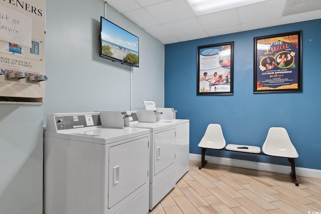 community laundry room with washer and dryer, baseboards, and light wood finished floors