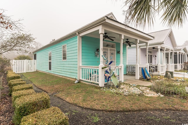 shotgun-style home featuring a porch, ceiling fan, and fence