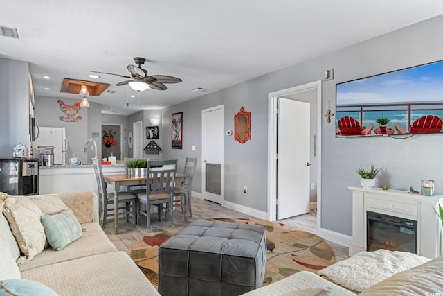 living area with ceiling fan, recessed lighting, a glass covered fireplace, and baseboards