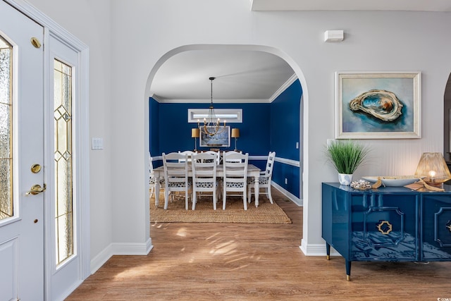 foyer entrance featuring wood-type flooring, an inviting chandelier, and crown molding