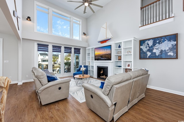 living room with a high ceiling, wood-type flooring, and ceiling fan