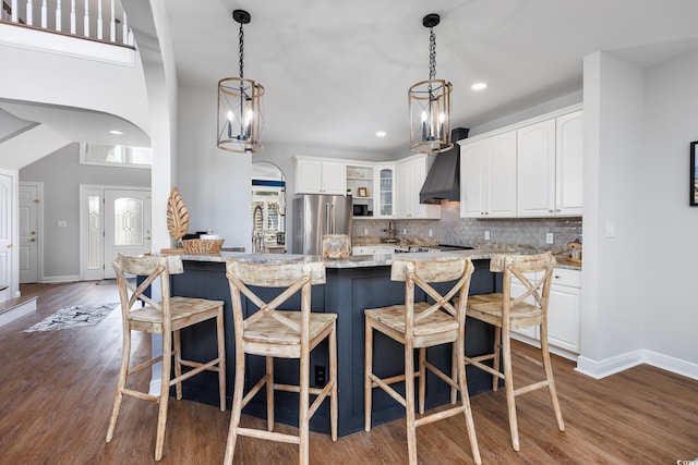 kitchen featuring white cabinetry, dark hardwood / wood-style floors, light stone countertops, decorative backsplash, and high end refrigerator