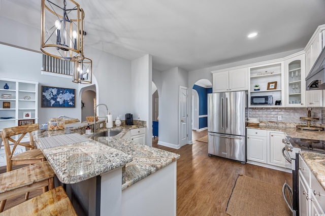 kitchen with stainless steel appliances, a kitchen island with sink, sink, and white cabinets