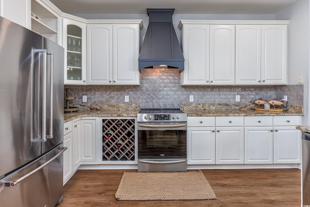 kitchen featuring white cabinetry, stainless steel appliances, stone counters, and premium range hood