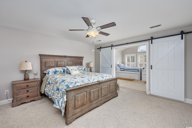 carpeted bedroom featuring ceiling fan and a barn door