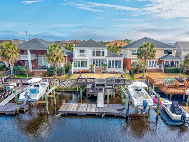 dock area featuring a balcony, a water view, and a lawn