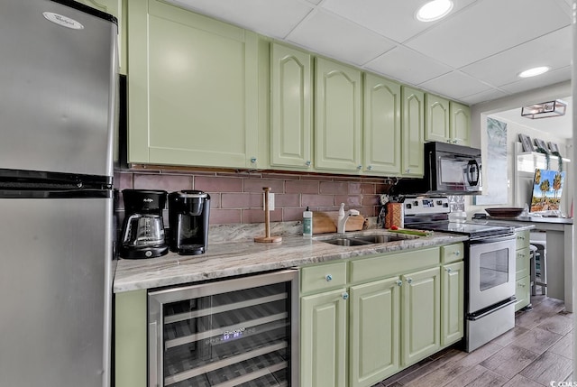 kitchen featuring sink, light hardwood / wood-style flooring, stainless steel appliances, beverage cooler, and decorative backsplash