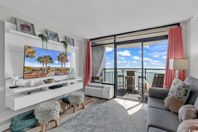 living room featuring hardwood / wood-style floors, a wall of windows, a wall mounted AC, and a water view