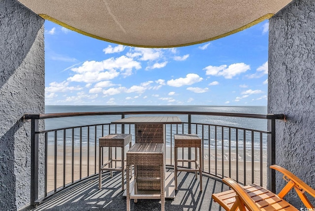 balcony featuring a beach view and a water view