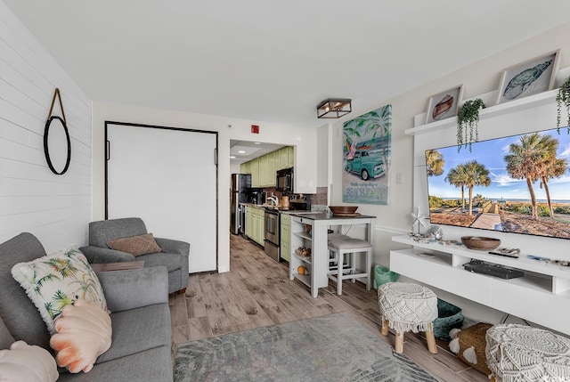 living room with light hardwood / wood-style flooring and wood walls