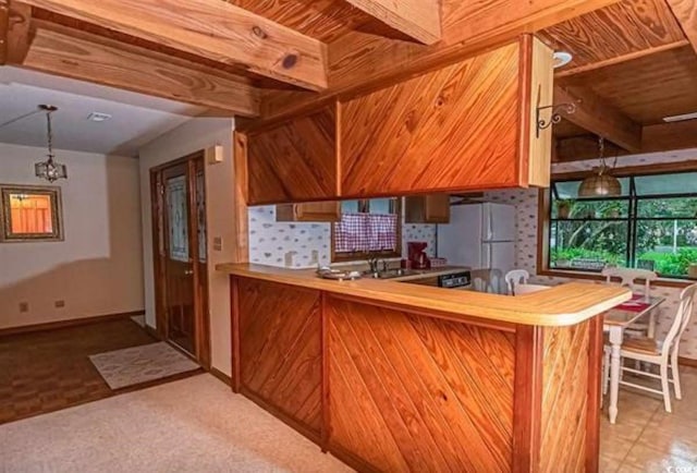 kitchen featuring pendant lighting, sink, decorative backsplash, white refrigerator, and kitchen peninsula