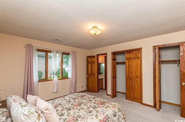 carpeted bedroom with two closets and a textured ceiling