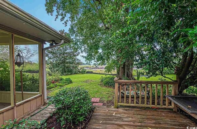 wooden deck with a lawn and a sunroom