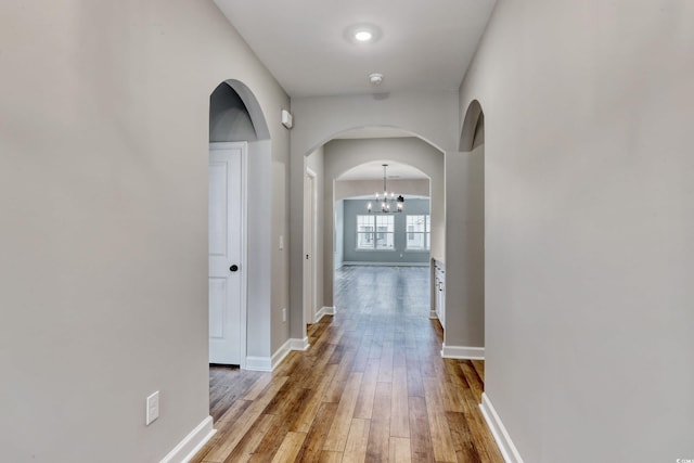 corridor featuring an inviting chandelier and light hardwood / wood-style flooring