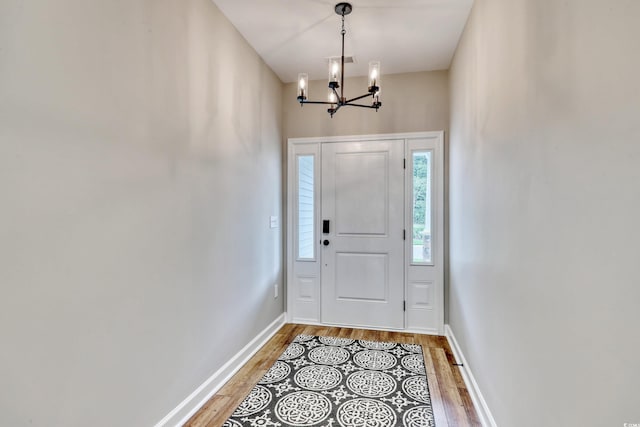 entryway with a wealth of natural light, a notable chandelier, and light hardwood / wood-style flooring