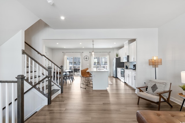 kitchen with stainless steel appliances, a kitchen island, a kitchen breakfast bar, white cabinets, and sink