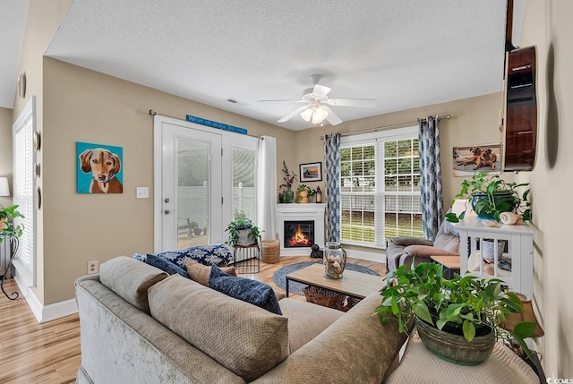 living room with ceiling fan, light hardwood / wood-style floors, and a textured ceiling