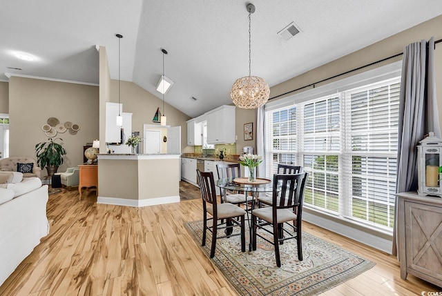 dining space with lofted ceiling, a notable chandelier, a textured ceiling, and light hardwood / wood-style flooring