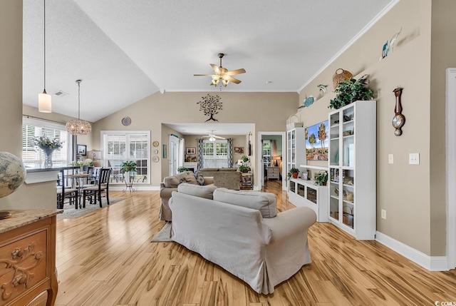 living room with lofted ceiling, ceiling fan with notable chandelier, light hardwood / wood-style flooring, and ornamental molding