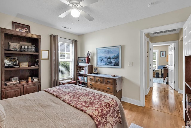 bedroom with ceiling fan, a textured ceiling, and light wood-type flooring