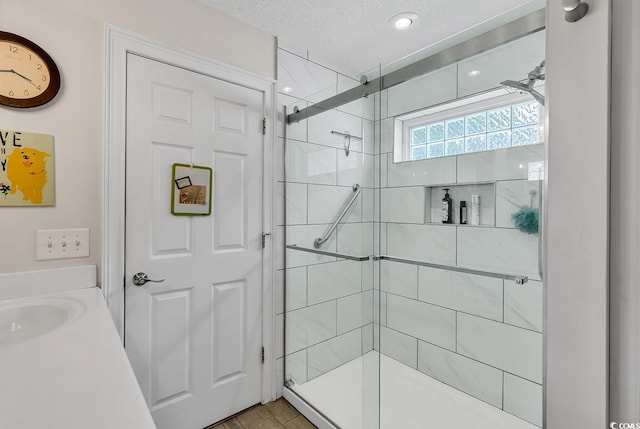 bathroom featuring a shower with door, vanity, and a textured ceiling