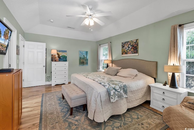 bedroom featuring hardwood / wood-style flooring, ceiling fan, and a tray ceiling