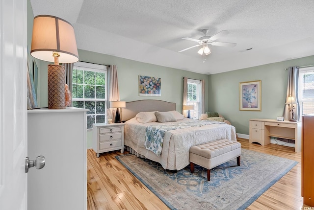 bedroom featuring ceiling fan, a textured ceiling, and light wood-type flooring