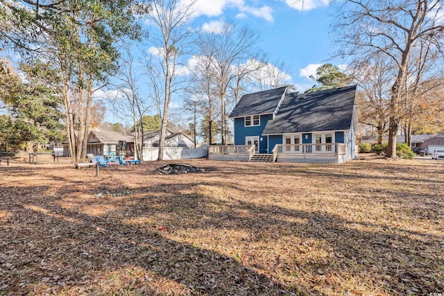 rear view of property featuring a wooden deck and a lawn