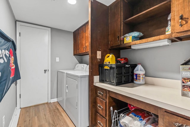 clothes washing area featuring independent washer and dryer, light hardwood / wood-style floors, and cabinets