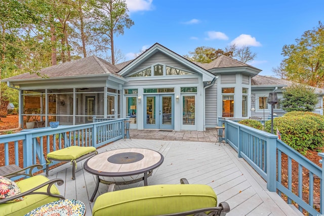 wooden deck featuring a sunroom and an outdoor fire pit