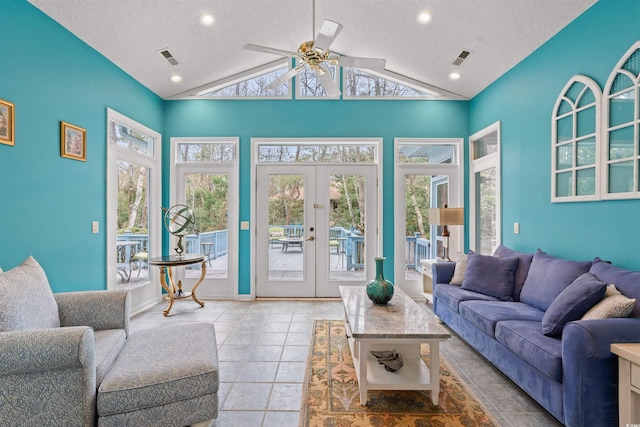 tiled living room featuring french doors, ceiling fan, lofted ceiling, and a textured ceiling