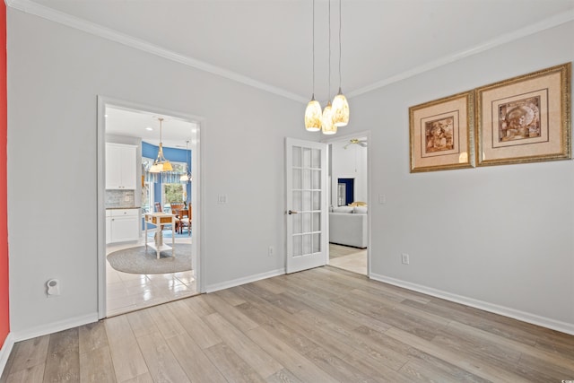 unfurnished dining area with crown molding, an inviting chandelier, light wood-type flooring, and french doors