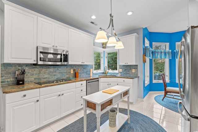 kitchen with sink, white cabinetry, light tile patterned floors, appliances with stainless steel finishes, and pendant lighting