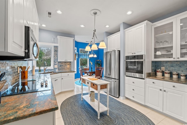 kitchen with sink, white cabinetry, hanging light fixtures, stainless steel appliances, and light tile patterned flooring