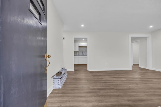 unfurnished living room featuring baseboards, wood finished floors, recessed lighting, and a sink
