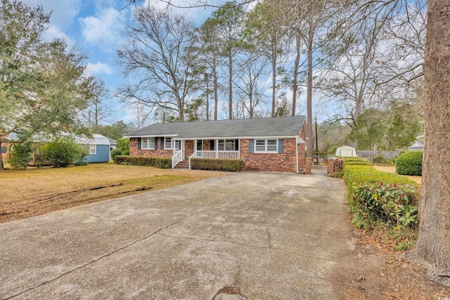 view of front of property featuring an outbuilding, driveway, a front yard, a porch, and a storage shed