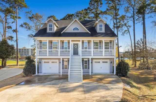 coastal home with a garage, stairway, a porch, and concrete driveway