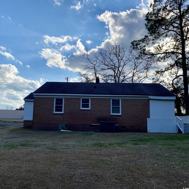 back of house with central AC and a lawn