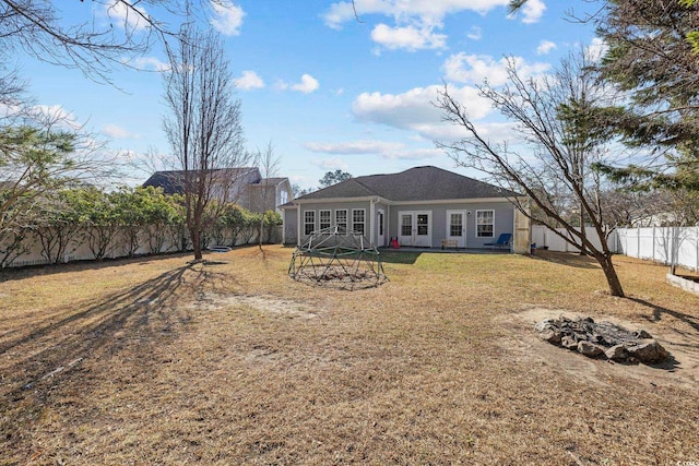 back of property with a fire pit and a lawn