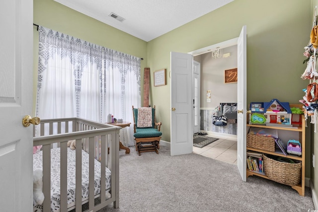 carpeted bedroom with a nursery area and a textured ceiling