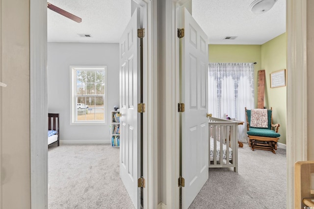 hall featuring light colored carpet and a textured ceiling