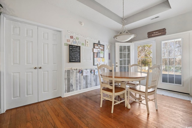 dining area featuring hardwood / wood-style flooring and a tray ceiling